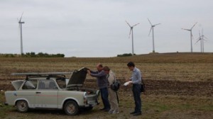 Solar-Trabi Marke Eigenbau vor modernen Windenergieanlagen